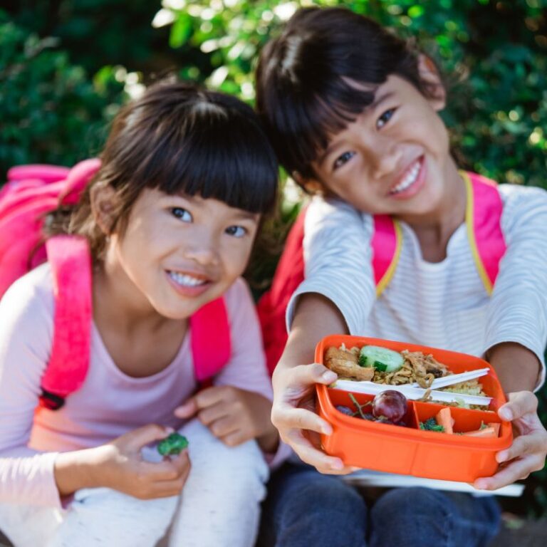 Two kids eating school lunches